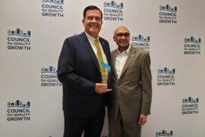 Emory Morsberger and board member Shiv Aggarwal pose for a photo. In Emory's hand is the Counil for Quality Growth award.